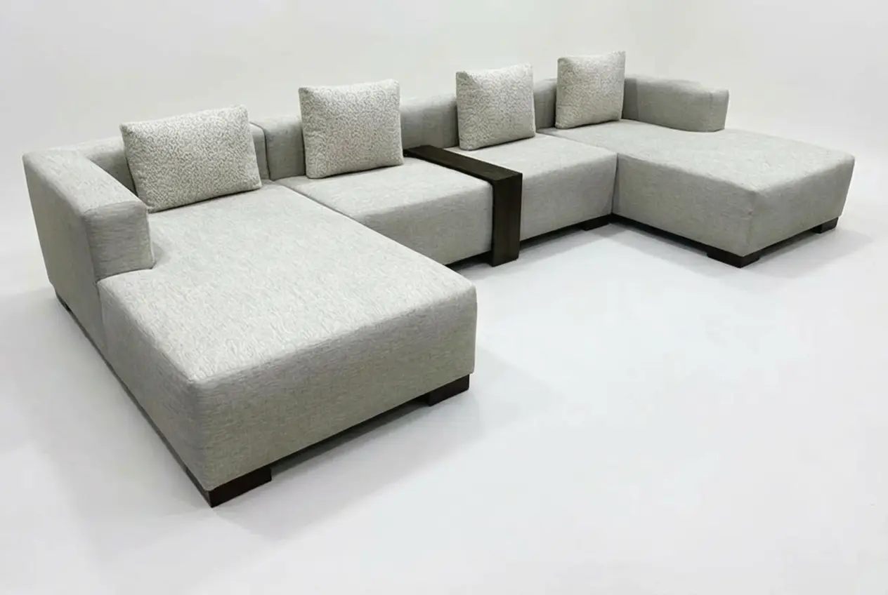 Large U-shaped light grey sectional sofa with middle wooden console table and double chaise lounges, isolated on white background for furniture stores in Sri Lanka.